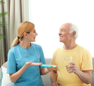 caregiver giving medicine to the senior man