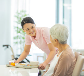 caregiver bringing food for the senior woman